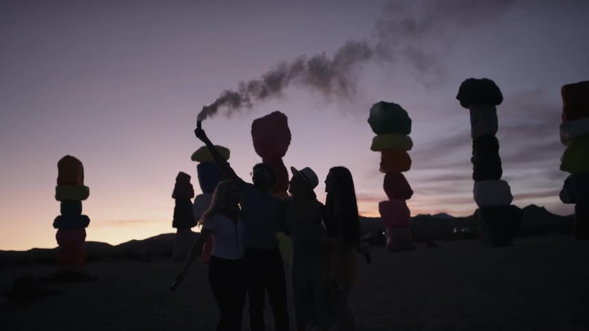 Man waves smoking tube over head of friends