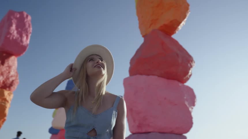 A young woman turns around and looks at the colored sculptures around her