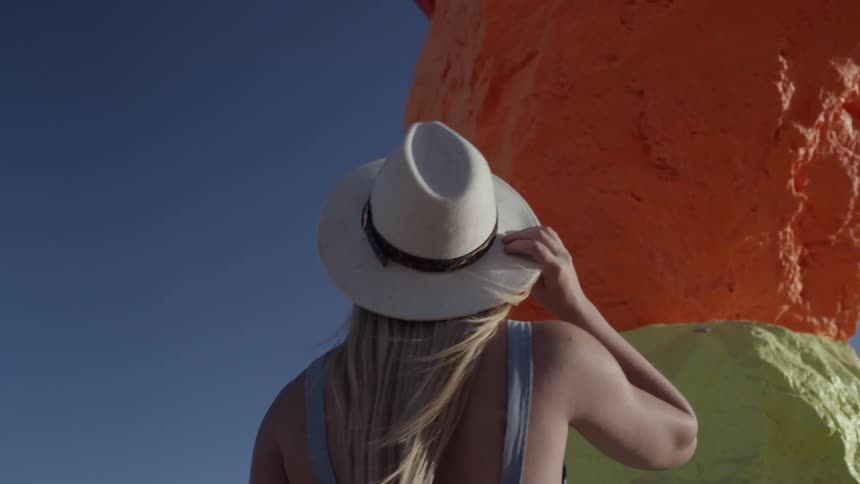 A young woman stands and looks at a big colorful sculpture