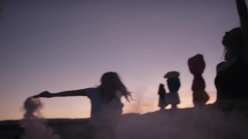 A group of people are celebrating with smoke bombs in the evening