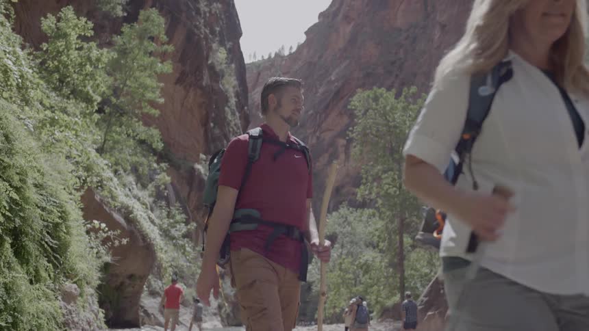 A group of people hike through a river and valley