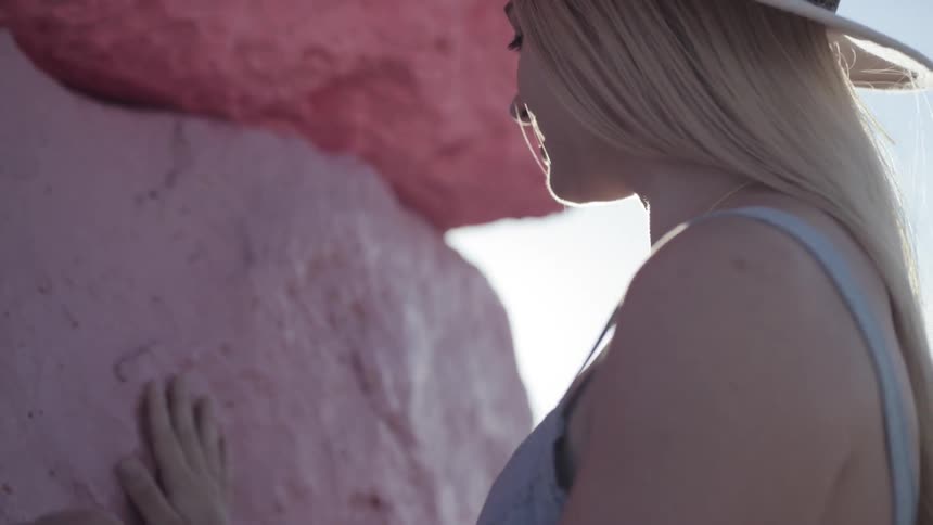 A woman touches a large rock
