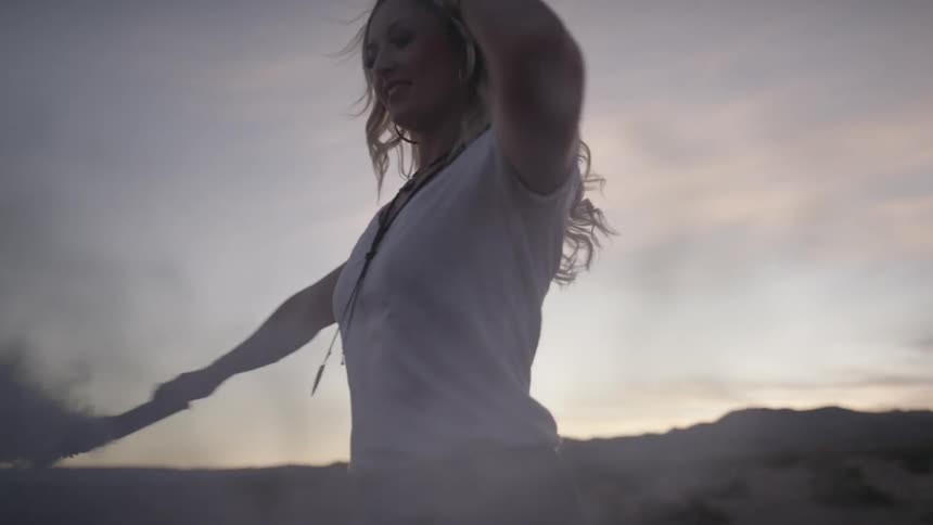 A woman dances holding a smoking tube