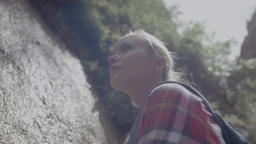 A hiker touches rock while looking up at the canyon walls