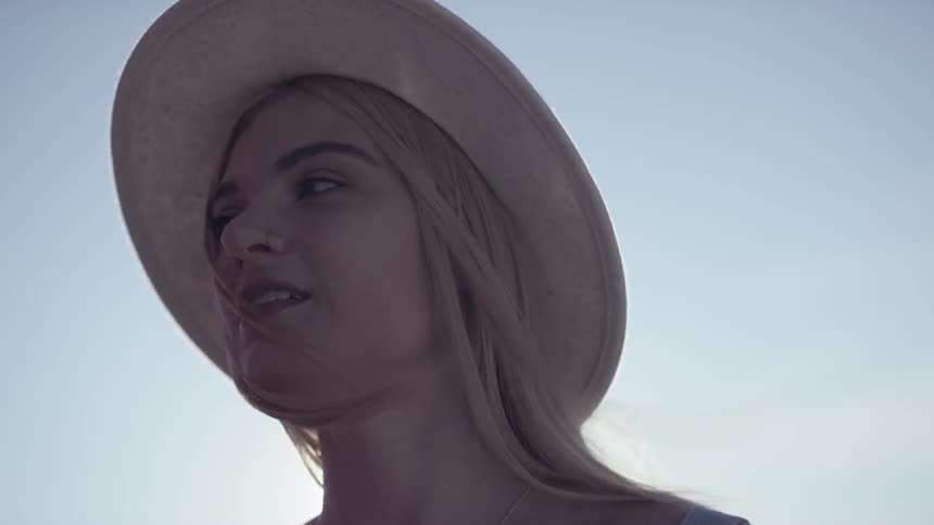 A white woman in a sun hat looks around her environment