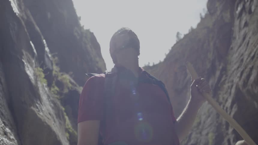 A man looks up at a cliff while he is hiking