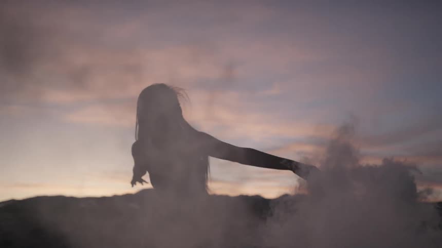 A young woman laughs while spinning around with a smoke bomb in her hand