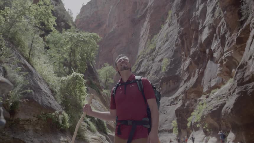 A man and a woman hiking and smiling between two cliffs
