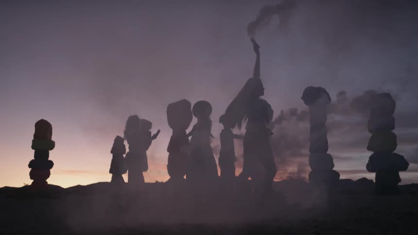 A group of people holding smoke bombs in the desert