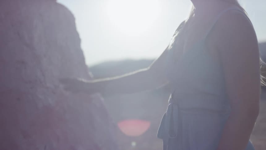 A woman with blonde hair wears a sun hat and looks at installations