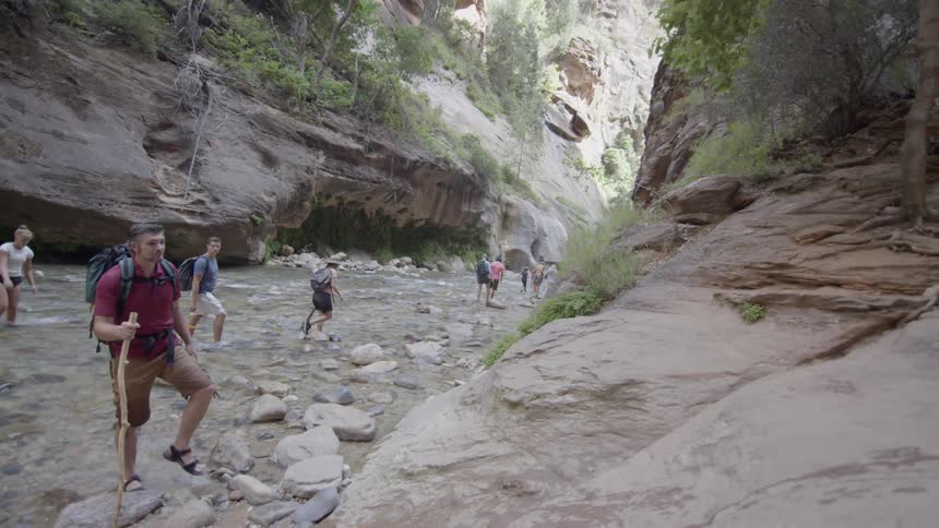 A group of hikers walking down a stream in a gorge