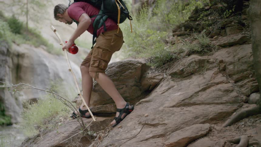 A man climbs up a rock and sits down