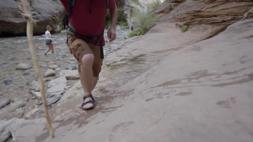 A hiker climbs out of the water and onto a large rock