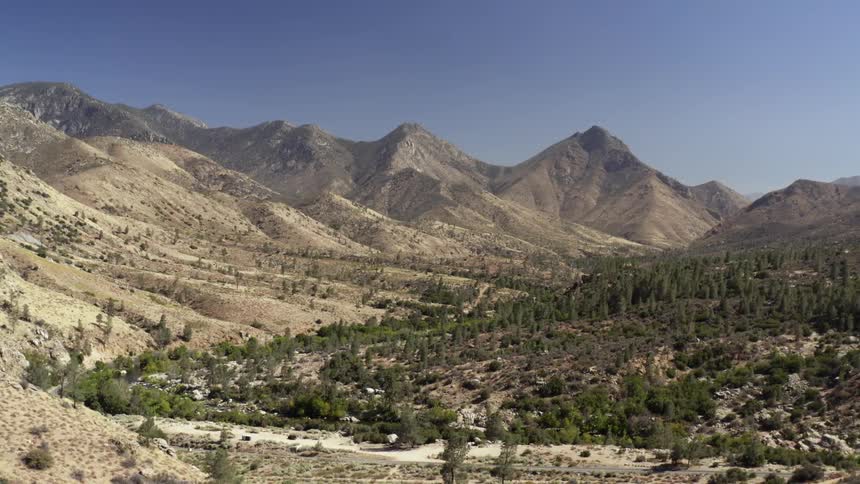 Scrub and trees cover slopes leading to higher mountains