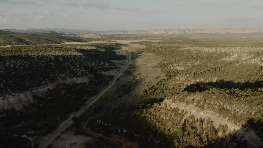 An aerial view of a landscape of mountain ridges hills and a long road