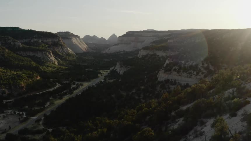 The sun shines over a forested valley