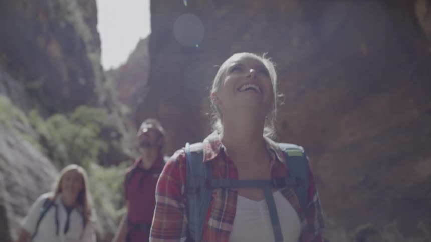 A group of hikers walk through a river at the base of mountains