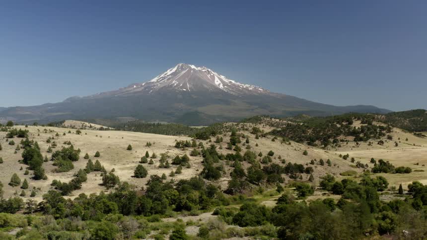 An aerial view of hills with a large mountain in the distance