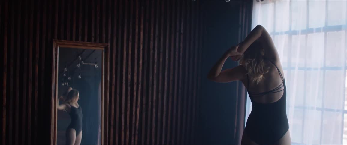 Blonde woman stretches her arms above her head before dancing in a room