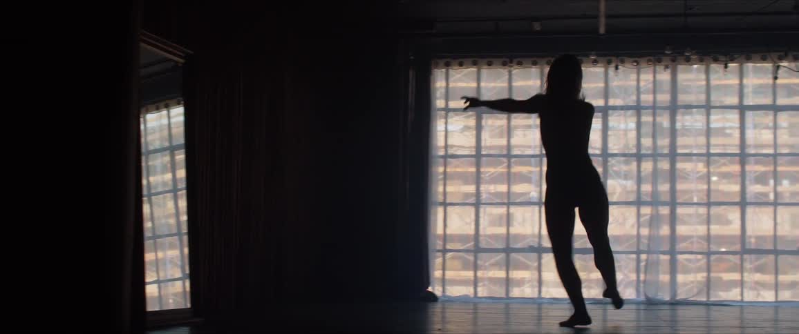 A young woman dances in a dark room