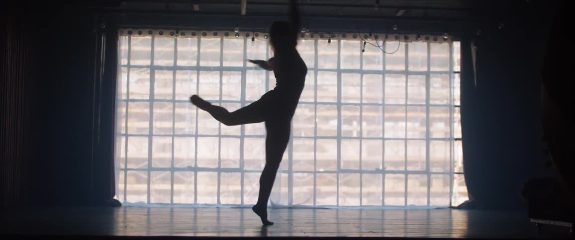 A woman dances in front of a floor to ceiling window