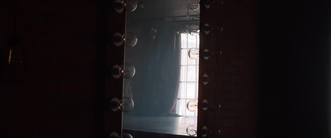 A woman dances in studio in front of a large mirror
