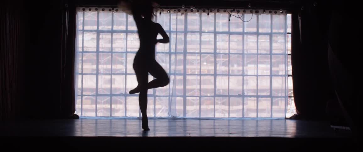 A female ballerina is dancing on stage and slips and falls after multiple turns in a row