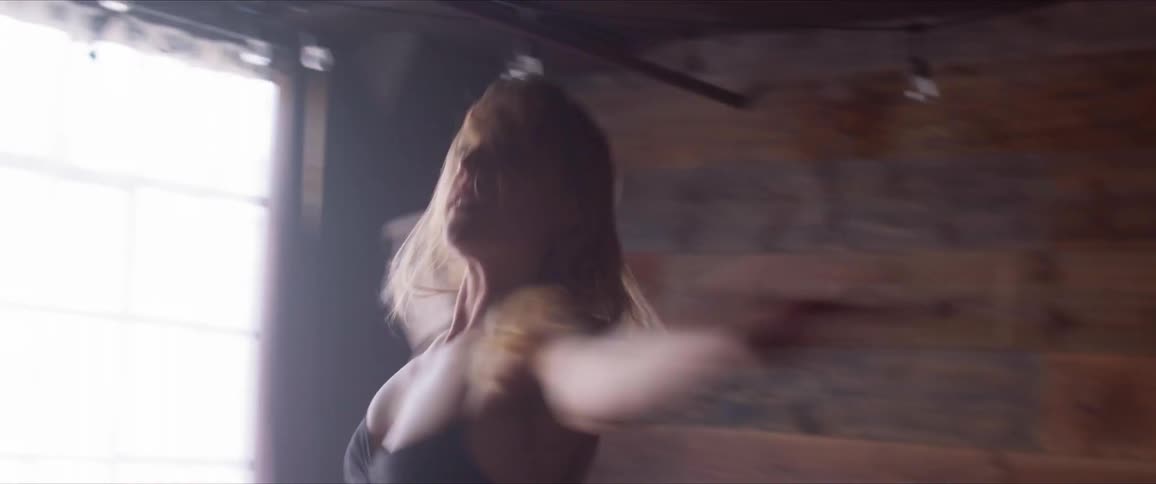 Blonde ballerina dances on the wooden floor in a room