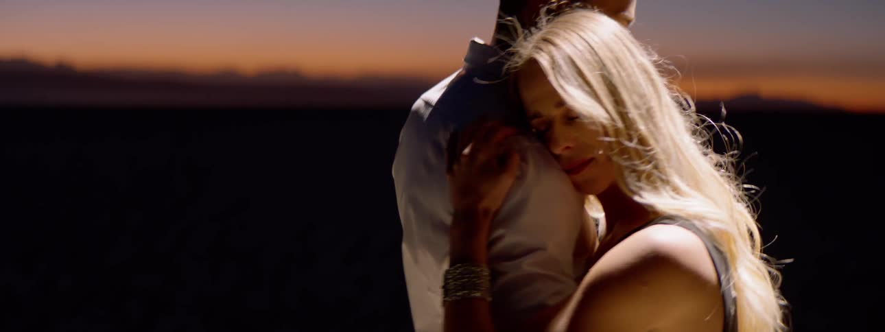 A man and woman slow dance at sunset