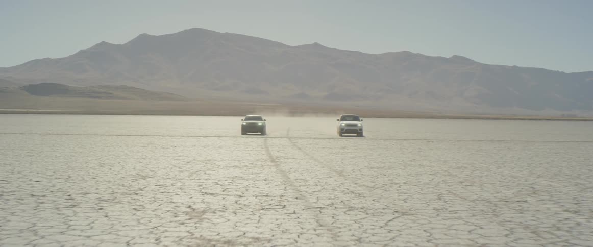 A pair of vehicles speeding side by side through the desert