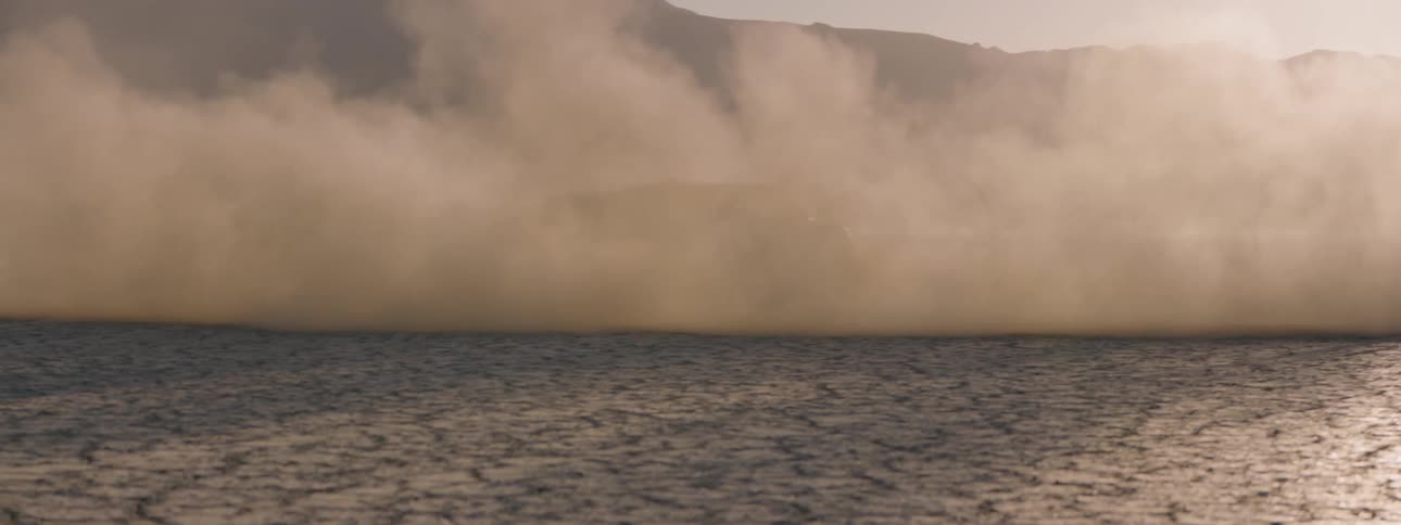 A thick dust cloud created by suvs driving in circles on the salt flats