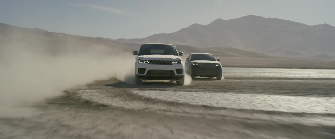 Two sport utility vehicles race in the desert