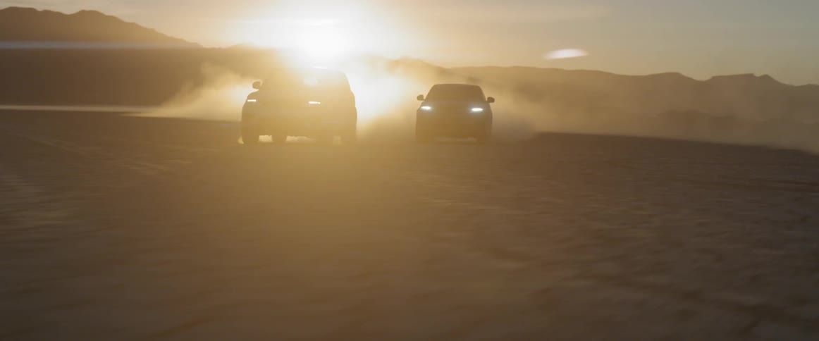Two cars speed across a desert plain