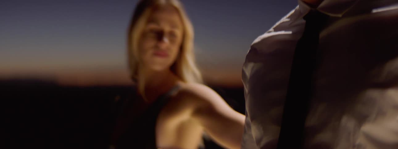 A woman rubs her hand along a mans shoulder all the way down to his hand