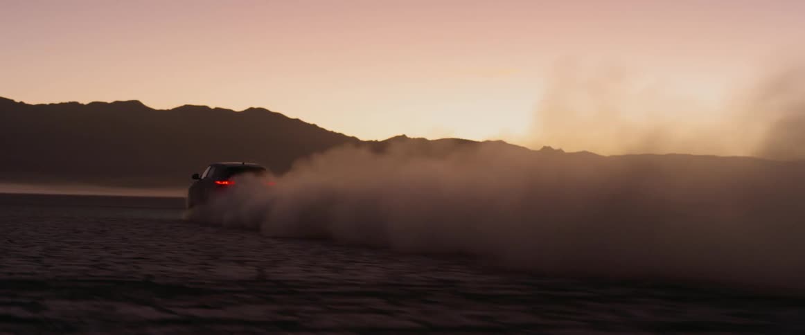Range rover sport drives away across the salt flats kicking up dust