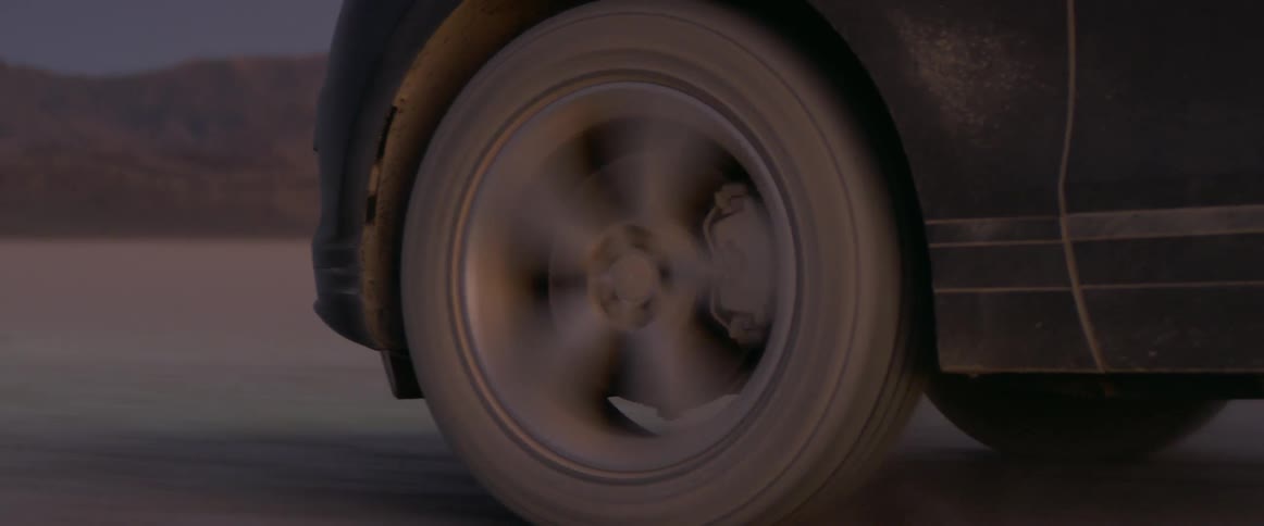 A dirty suv tire spins across the dirt road