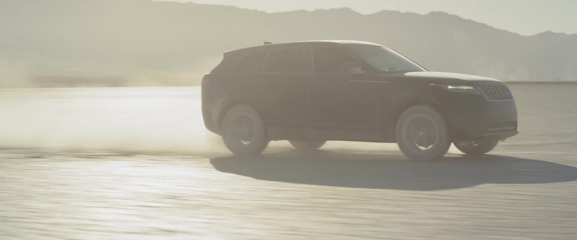 Two sport utility vehicles speed across a barren desert landscape