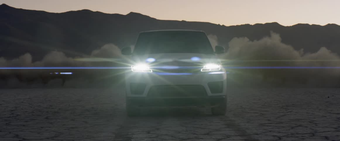A small vehicle does donuts around an suv in the dark desert