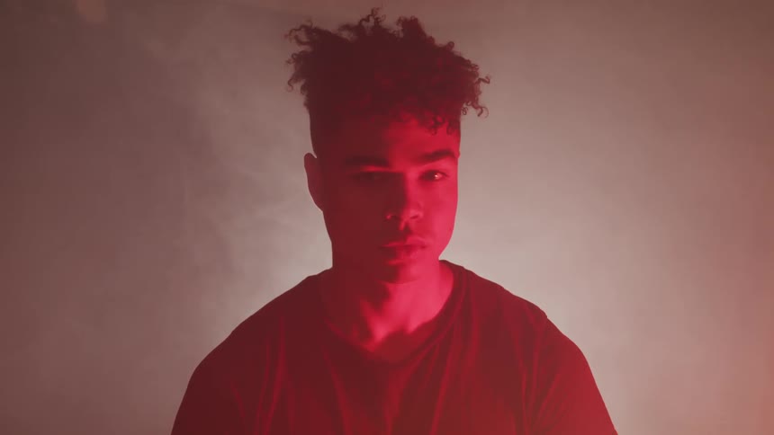A man is standing in a dark smoke filled room