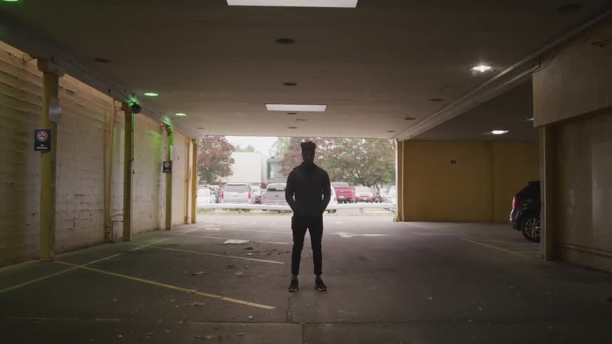 A man stands inside a parking garage