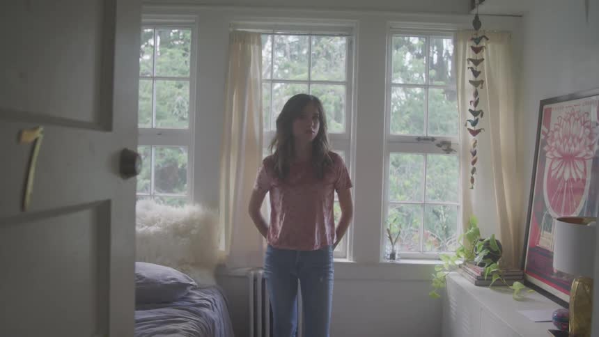 A woman is standing in her bedroom