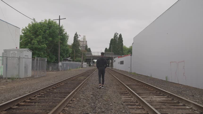 A man walking between two train tracks