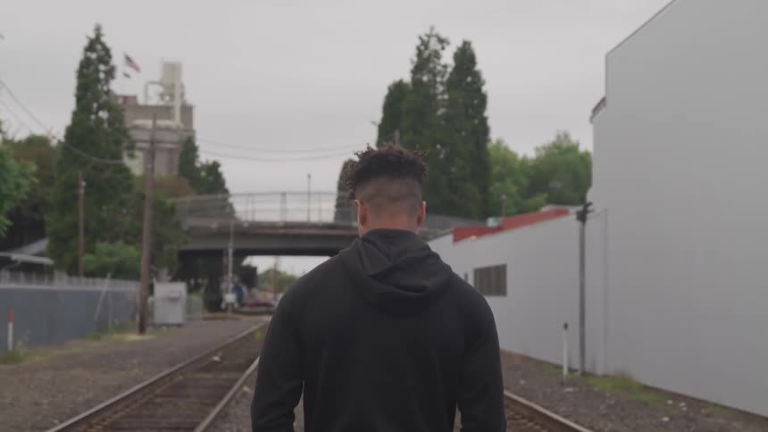 A young man walks down the train tracks
