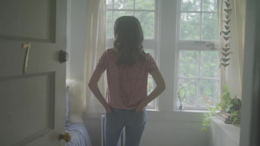 A woman looking in a room with her hands in her back pockets