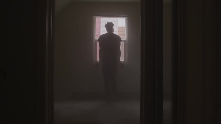 Man stands in front of a window as he looks outside