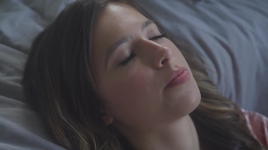 A woman laying in bed staring at the ceiling then closing her eyes