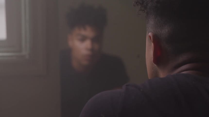 A man is looking in the mirror in his bathroom