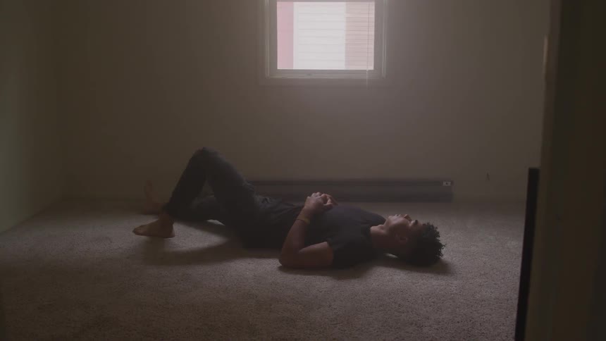 A man lays on the floor in an empty bedroom