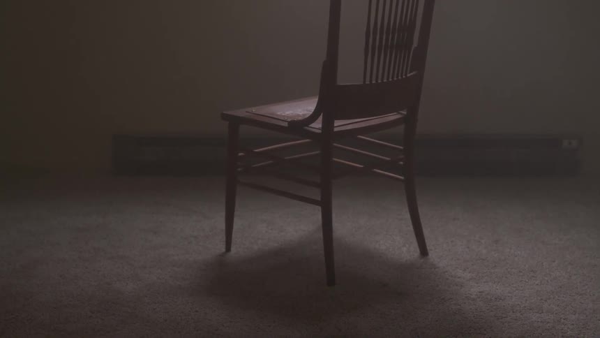 Straight wooden chair sits in empty shadowy room
