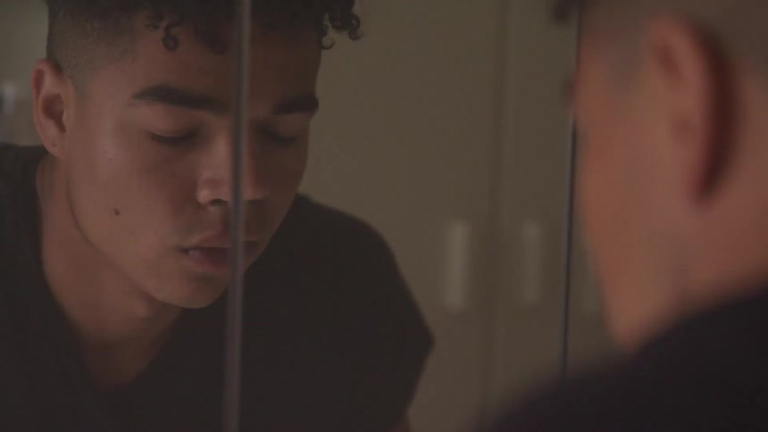A black teen faces a mirror with his eyes closed